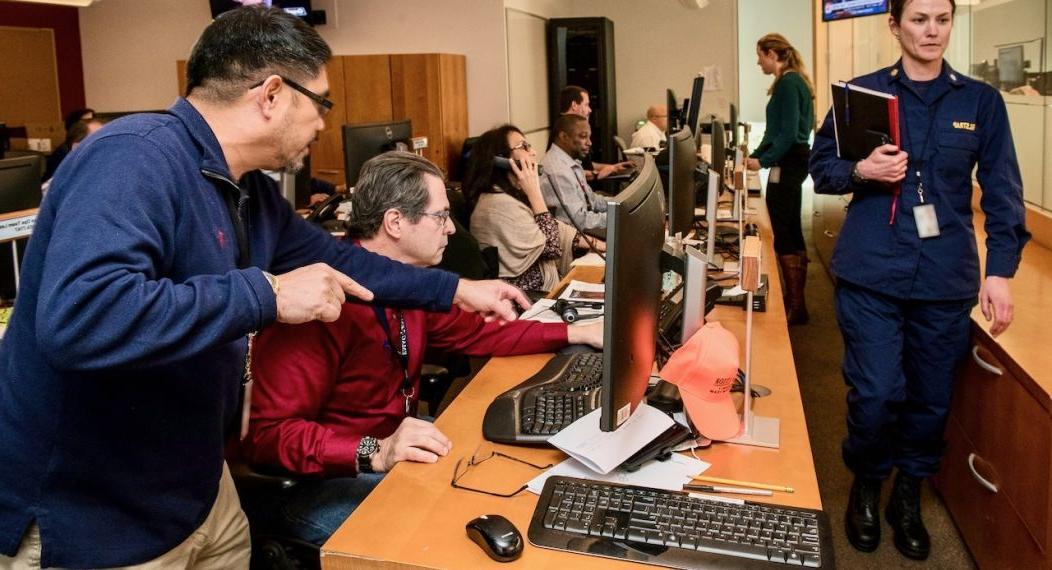 An emergency response team is shown working at their computer monitors.