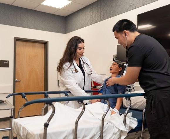 Photo shows two nursing students at Pacific's School of Health Science working with a manikin. 